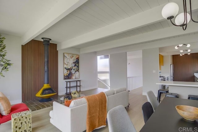 living area featuring an inviting chandelier, beam ceiling, and wood finished floors