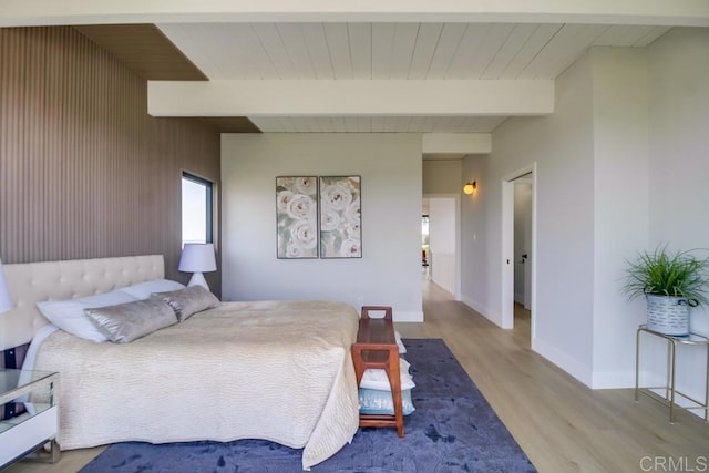 bedroom with baseboards, beamed ceiling, and wood finished floors
