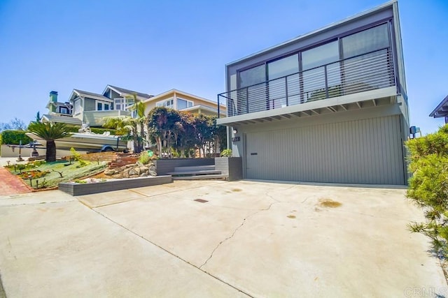 view of front of property featuring concrete driveway, an attached garage, and a balcony