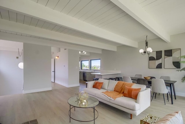 living area featuring baseboards, a notable chandelier, beam ceiling, and light wood-style floors