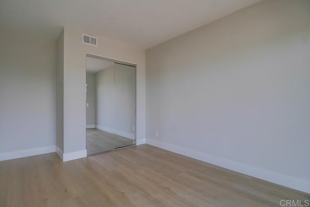 unfurnished room featuring baseboards, light wood-type flooring, and visible vents