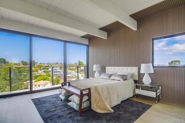 bedroom featuring visible vents, wood walls, beam ceiling, and wood finished floors