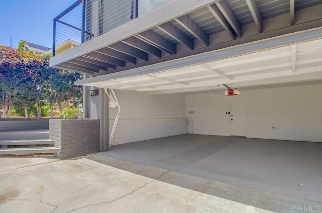 garage with an attached carport, driveway, and a garage door opener