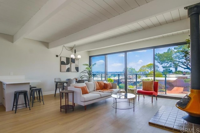 living area with baseboards, light wood-style flooring, a wealth of natural light, and beamed ceiling
