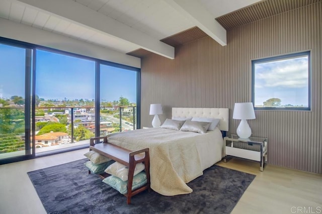 bedroom featuring radiator, wood finished floors, and beamed ceiling