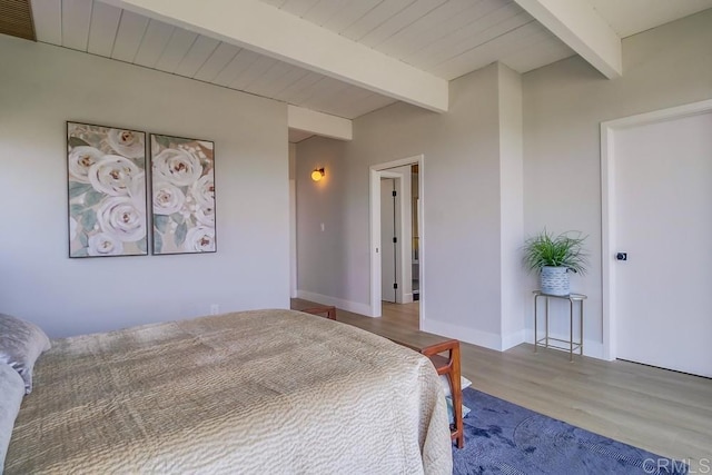 bedroom featuring baseboards, beamed ceiling, visible vents, and wood finished floors