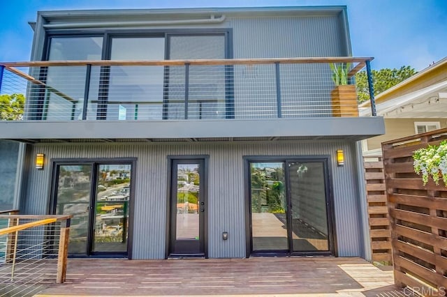 rear view of house featuring a balcony and a deck