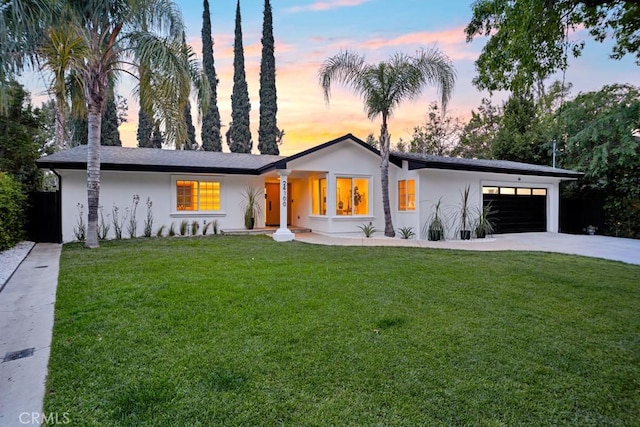 mid-century inspired home with a garage, stucco siding, driveway, and a front yard