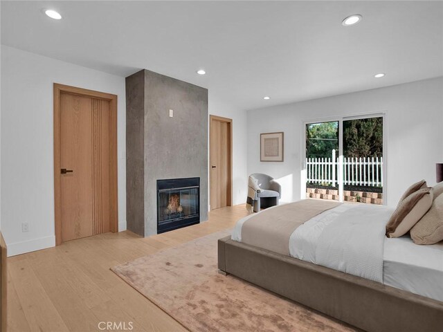 bedroom with access to outside, a fireplace, recessed lighting, and wood finished floors