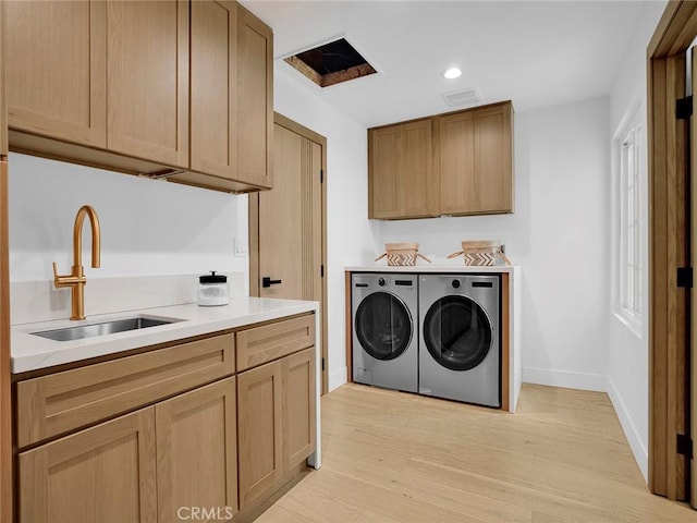 laundry room featuring cabinet space, a sink, baseboards, light wood finished floors, and separate washer and dryer