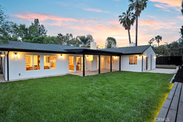rear view of property featuring a lawn, an attached garage, and stucco siding