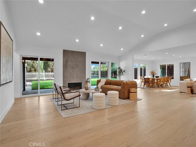 living room featuring a fireplace, recessed lighting, high vaulted ceiling, and light wood-type flooring