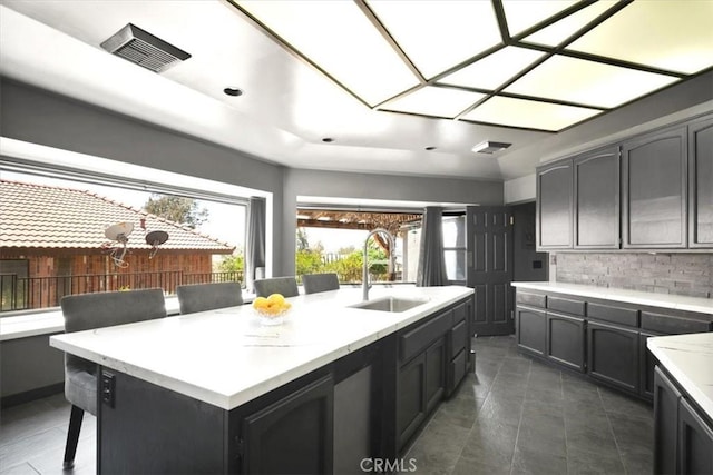 13784 Choco Rd, Apple Valley, CA 92307 - kitchen featuring a sink, backsplash, a breakfast bar area, light stone counters, and a center island with sink