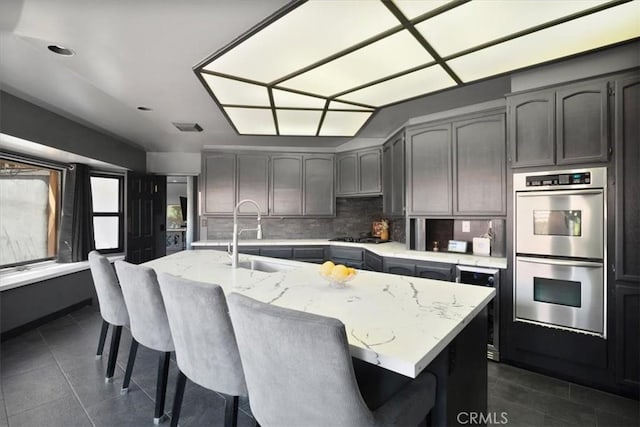 13784 Choco Rd, Apple Valley, CA 92307 - kitchen with stainless steel appliances, a sink, decorative backsplash, light stone countertops, and dark tile patterned flooring