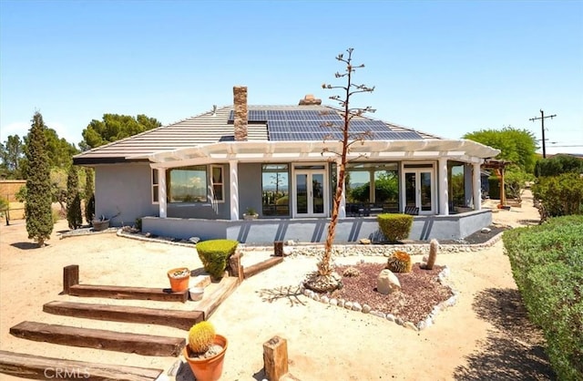 13784 Choco Rd, Apple Valley, CA 92307 - back of house featuring french doors, a pergola, roof mounted solar panels, a patio, and a chimney