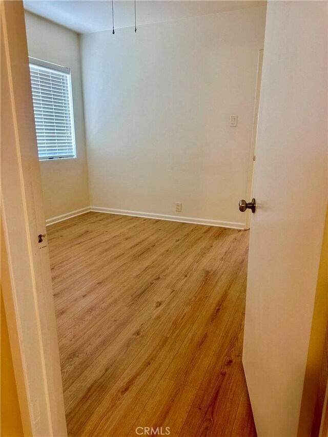 unfurnished room with baseboards and light wood-style flooring