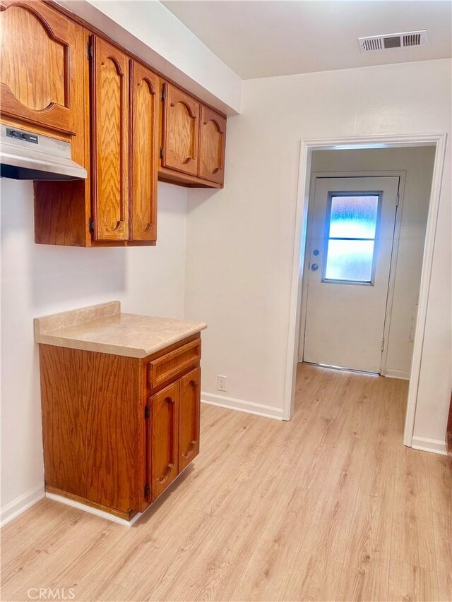 kitchen featuring light wood finished floors, brown cabinets, and visible vents