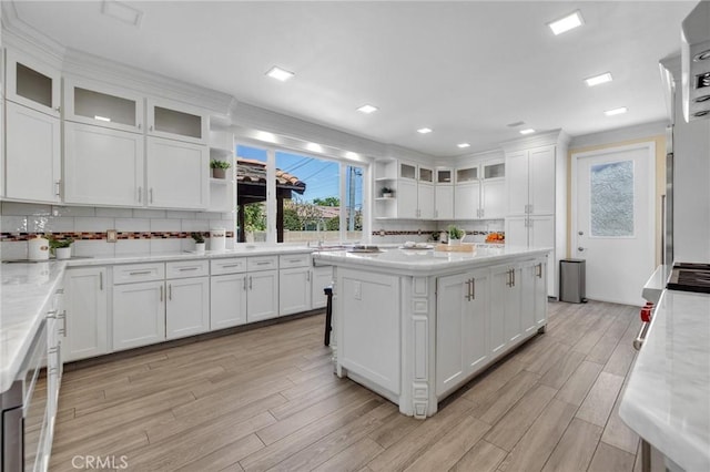 9371 Florence Ave, Downey, CA 90240 - kitchen featuring open shelves, light wood-style floors, a center island, white cabinetry, and backsplash