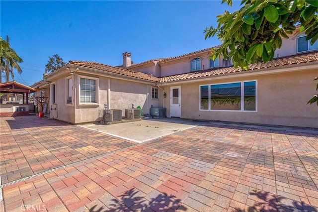 9371 Florence Ave, Downey, CA 90240 - rear view of property featuring stucco siding, a chimney, central AC, and a patio area