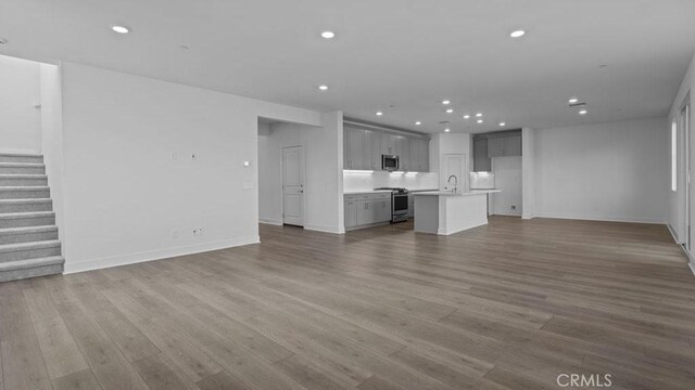 33328 Rusty Ct, French Valley, CA 92596 - unfurnished living room with wood finished floors, baseboards, stairway, recessed lighting, and a sink