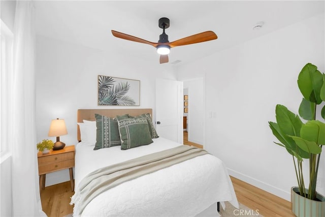 bedroom with a ceiling fan, baseboards, and wood finished floors