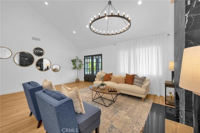 living area featuring a notable chandelier, high vaulted ceiling, recessed lighting, baseboards, and wood finished floors