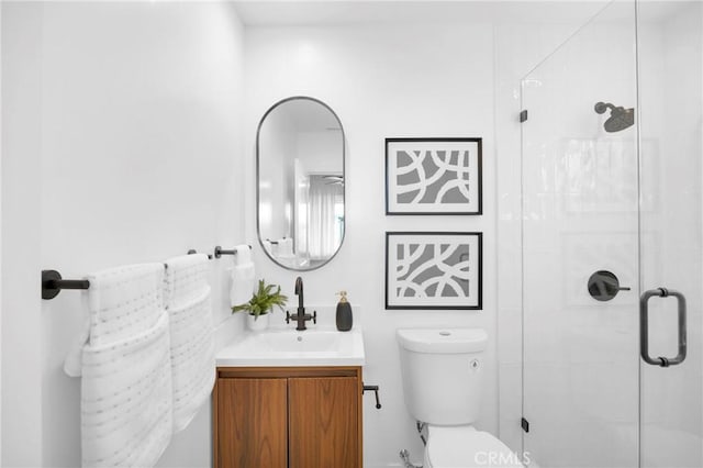 bathroom featuring toilet, a shower stall, and vanity