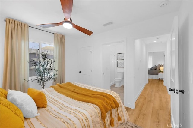 bedroom featuring ceiling fan, baseboards, ensuite bathroom, light wood-type flooring, and visible vents