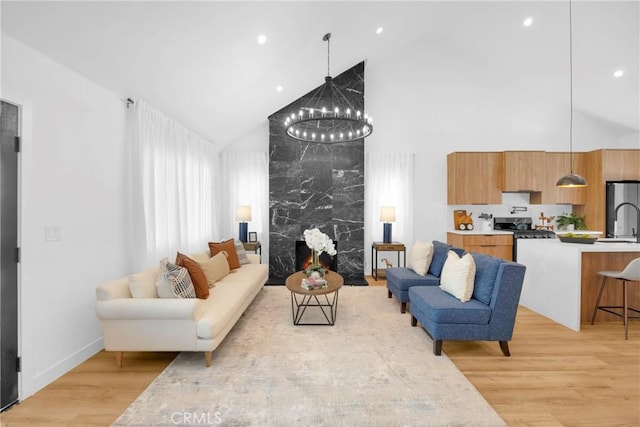 living room with an inviting chandelier, baseboards, high vaulted ceiling, recessed lighting, and light wood finished floors