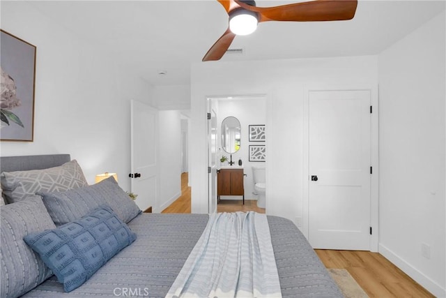 bedroom with baseboards, ceiling fan, wood finished floors, and connected bathroom