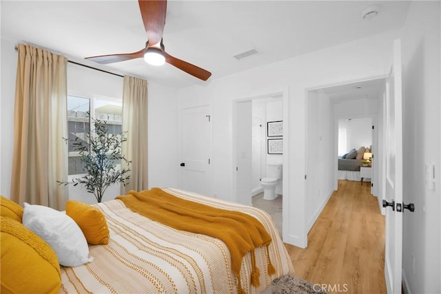 bedroom with visible vents, baseboards, ensuite bathroom, ceiling fan, and light wood-type flooring