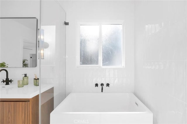 bathroom with a tub to relax in and vanity