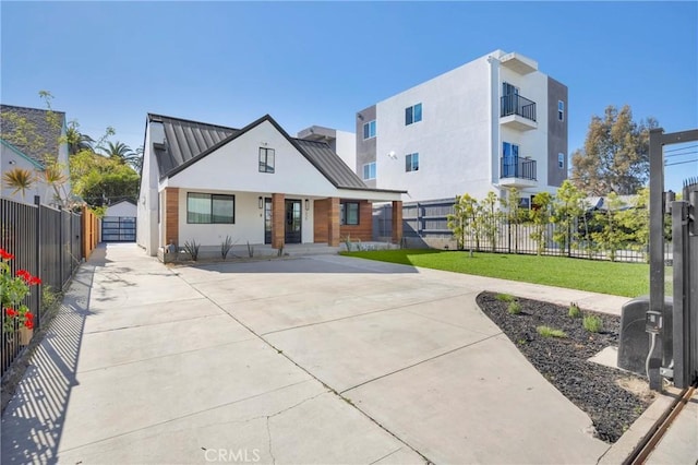modern farmhouse featuring fence, stucco siding, a front yard, a standing seam roof, and metal roof