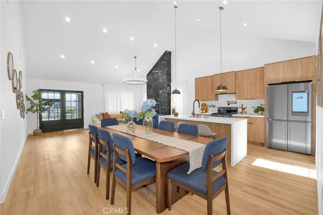 dining room featuring recessed lighting, high vaulted ceiling, a notable chandelier, and light wood-type flooring