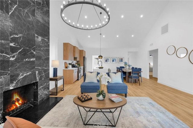 living area featuring high vaulted ceiling, visible vents, baseboards, and light wood finished floors