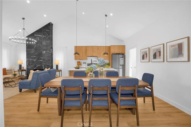 dining room featuring high vaulted ceiling, a chandelier, baseboards, and light wood-type flooring