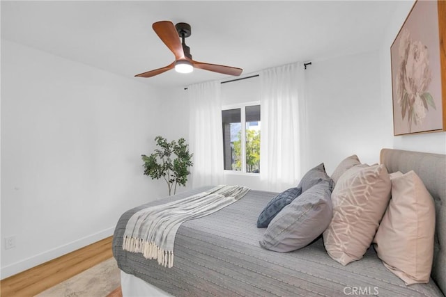bedroom with light wood-type flooring, a ceiling fan, and baseboards