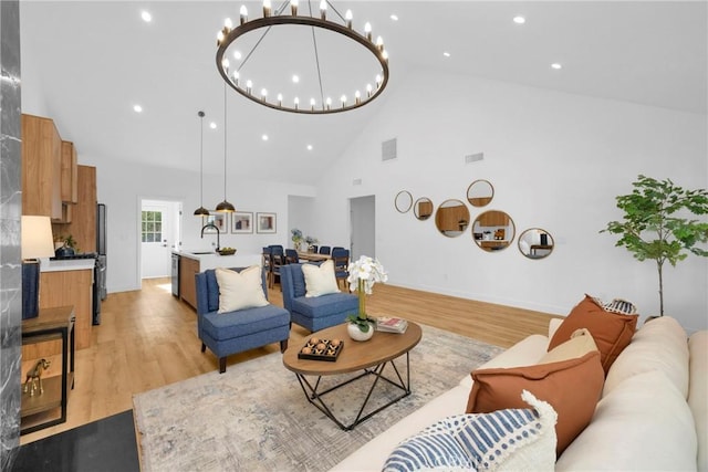 living room with an inviting chandelier, light wood finished floors, high vaulted ceiling, recessed lighting, and visible vents