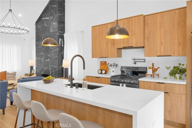 335 N Harvard Blvd, Los Angeles, CA 90004 - kitchen featuring stainless steel gas range oven, modern cabinets, a chandelier, light countertops, and a breakfast bar