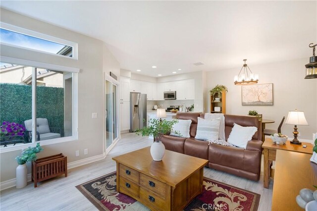 living area featuring recessed lighting, baseboards, an inviting chandelier, and light wood-style flooring