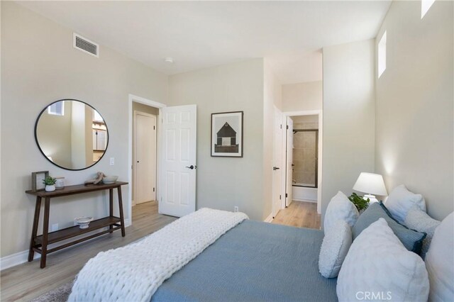 bedroom with visible vents, baseboards, ensuite bathroom, and light wood-type flooring