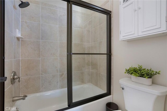 bathroom with combined bath / shower with glass door and toilet