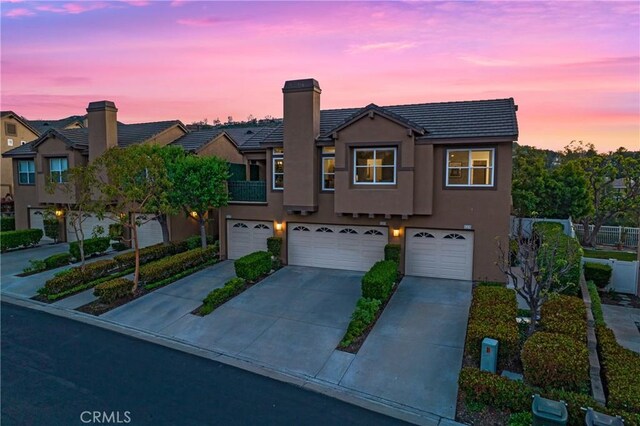 view of property featuring fence, an attached garage, stucco siding, concrete driveway, and a tiled roof