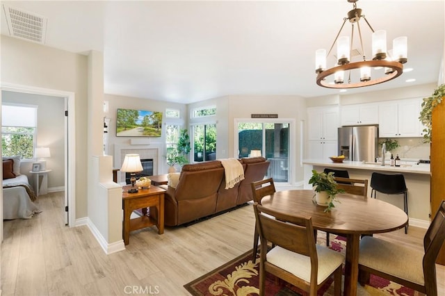 dining space with visible vents, plenty of natural light, a tile fireplace, and light wood-type flooring