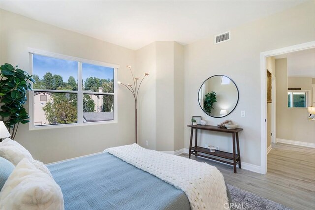 bedroom with baseboards, visible vents, and wood finished floors