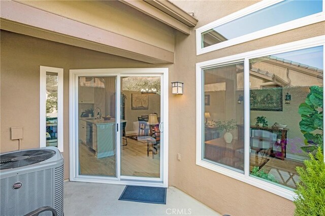 doorway to property featuring central AC unit and stucco siding