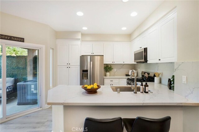 kitchen featuring white cabinetry, a peninsula, light stone countertops, and stainless steel appliances