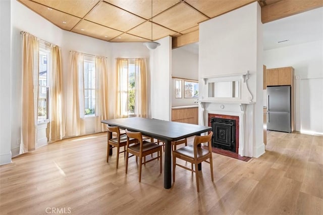 dining room featuring baseboards, a fireplace with flush hearth, and light wood-type flooring