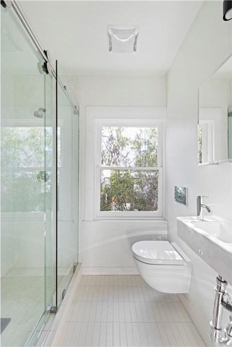 bathroom with toilet, tile patterned flooring, and a stall shower