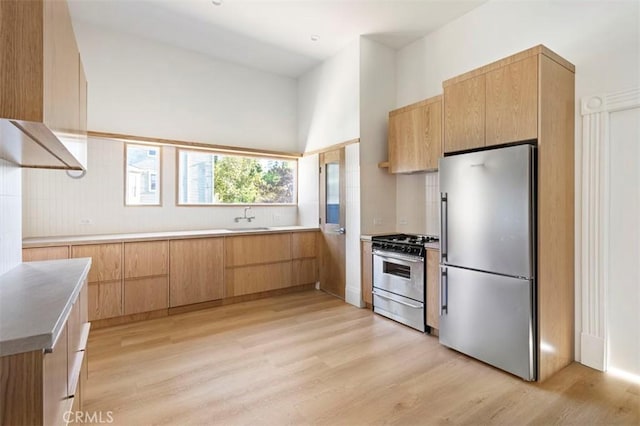 kitchen featuring stainless steel appliances, modern cabinets, a sink, and light wood-type flooring
